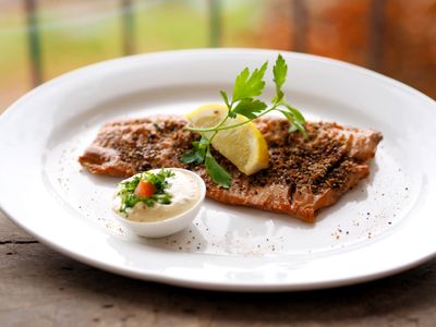 Geräuchertes Karpfenfilet auf einem weißen Teller mit Petersilien- und Zitronengarnitur