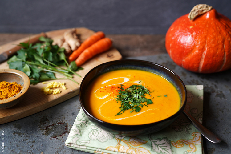 Kürbissuppe in einem schwarzen Teller mit Gemüsedeko