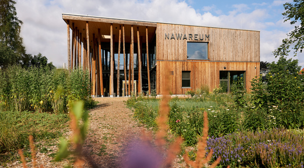 KI generiert: Modernes Holzgebäude mit Garten, Schriftzug "NAWAREUM".