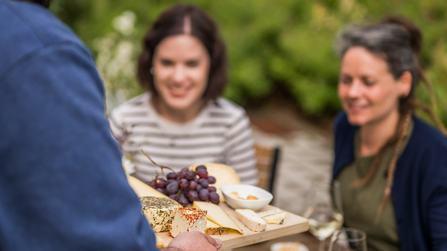 KI generiert: Eine Käseplatte mit Trauben wird zwei Personen am Tisch serviert.