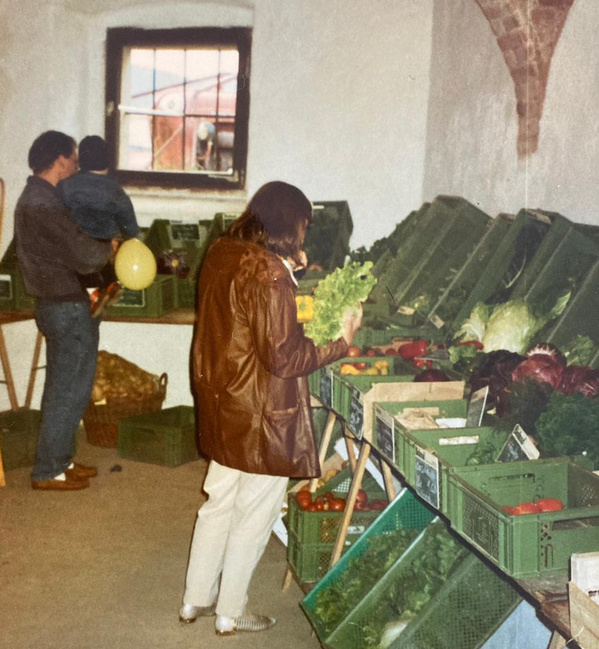 KI generiert: Menschen kaufen frisches Gemüse in einem Laden mit Holzkisten.