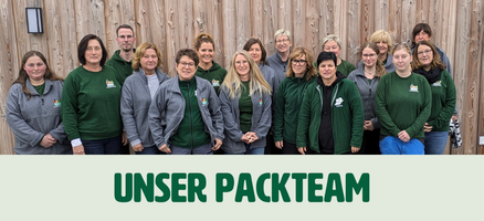 KI generiert: Eine Gruppe von fünfzehn Personen posiert vor einer Holzwand, vermutlich ein Team, da sie ähnliche Kleidung tragen. Darunter steht der Text "UNSER PACKTEAM".