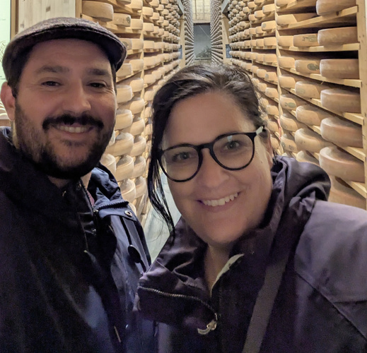 KI generiert: Zwei Personen in einem Käsekeller, umgeben von reifenden Käselaiben.