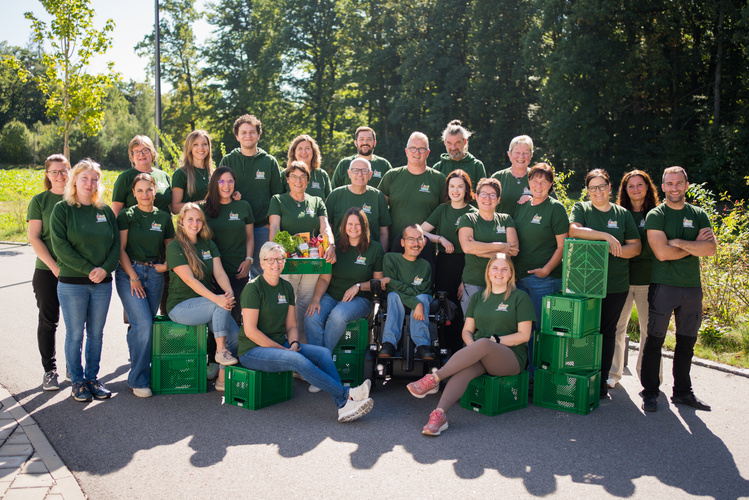 KI generiert: Eine Gruppe von Menschen in grünen T-Shirts mit Kisten posiert im Freien.