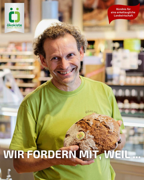 KI generiert: Ein Mann hält Brot in einem Geschäft mit Text: "WIR FORDERN MIT, WEIL ...".
