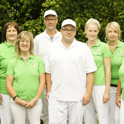 KI generiert: Eine Gruppe von Menschen posiert draußen, einige tragen grüne Polohemden.
