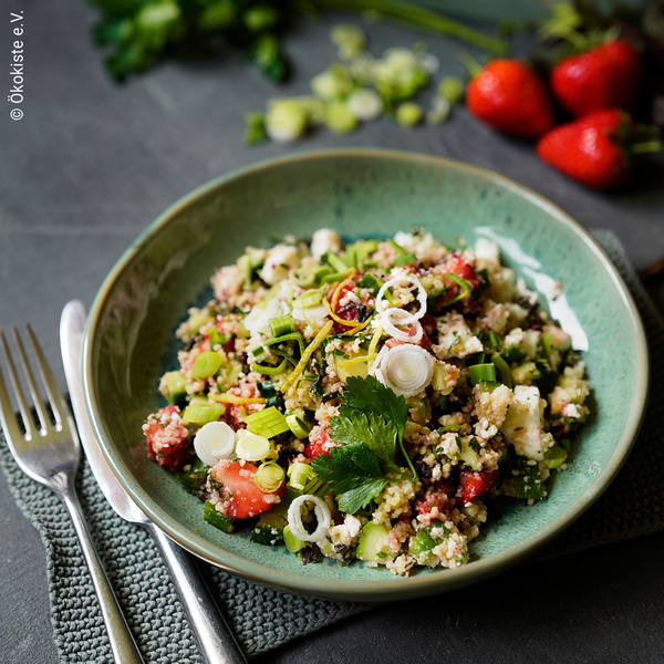 KI generiert: Ein Teller mit einem frischen, bunten Couscous-Salat, garniert mit Kräutern. Text: "© Ökokiste e.V."