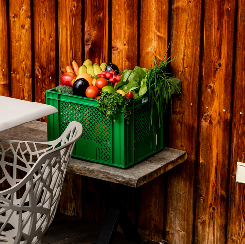 KI generiert: Eine grüne Kiste mit frischem Obst und Gemüse steht auf einem Holzbank.