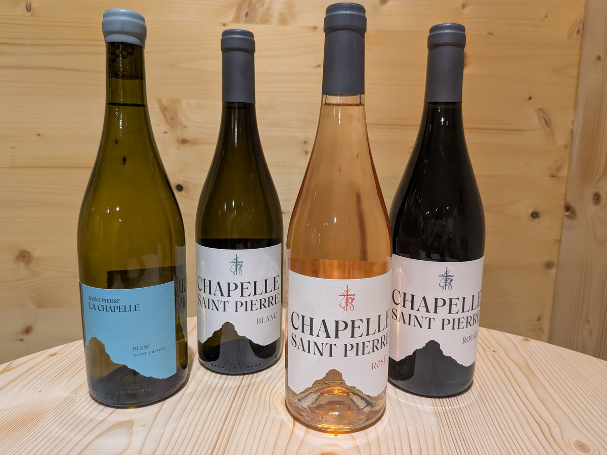 KI generiert: Vier Weinflaschen auf einem Holztisch. Label: "CHAPELLE SAINT PIERRE".