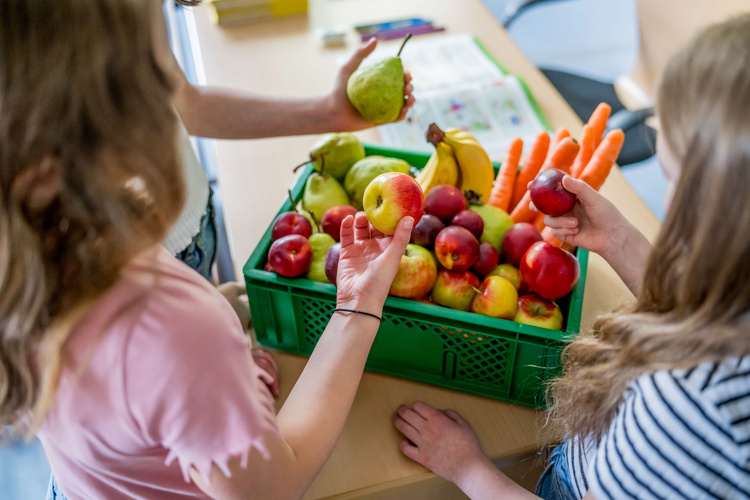 KI generiert: Kinder betrachten eine Kiste mit frischem Obst und Gemüse.