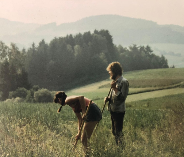 KI generiert: Zwei Personen arbeiten mit Gartenwerkzeugen auf einem Feld in ländlicher Landschaft.