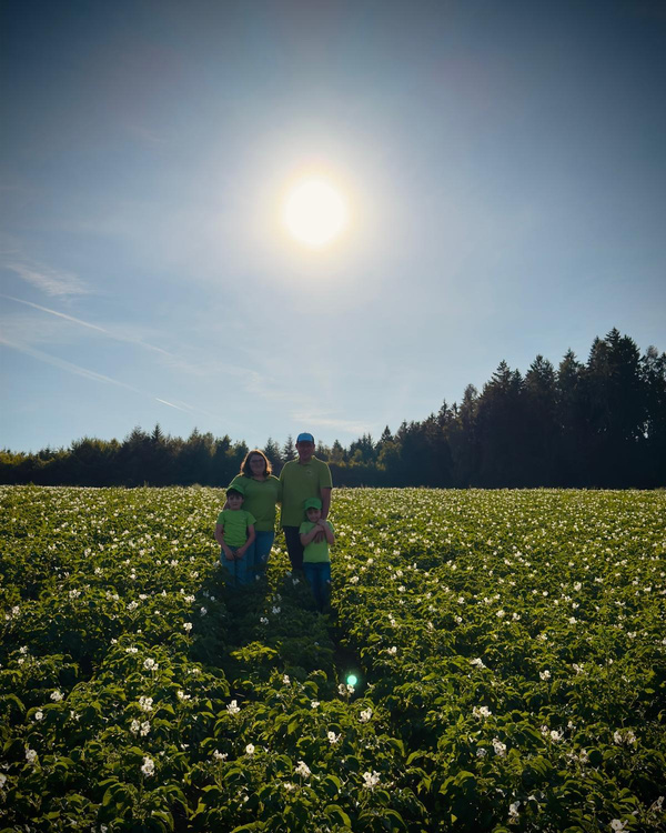 KI generiert: Eine Familie steht auf einem Blumenfeld unter blauem Himmel mit der Sonne im Hintergrund.