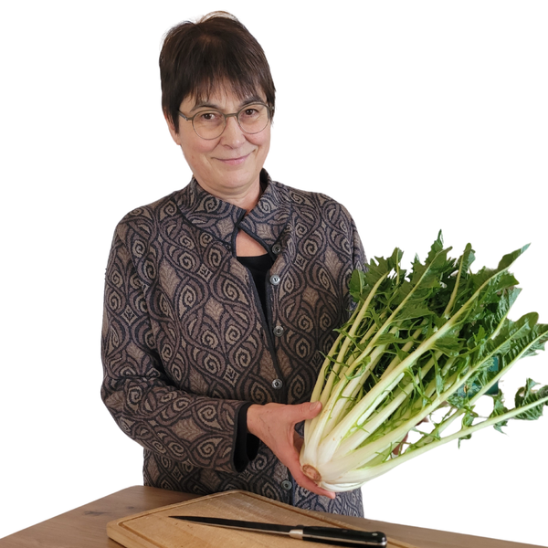 KI generiert: Eine Person hält einen großen Bund grüner Blätter, vermutlich ein Gemüse, in den Händen. Vor ihr auf dem Tisch liegen ein Schneidebrett und ein Messer.