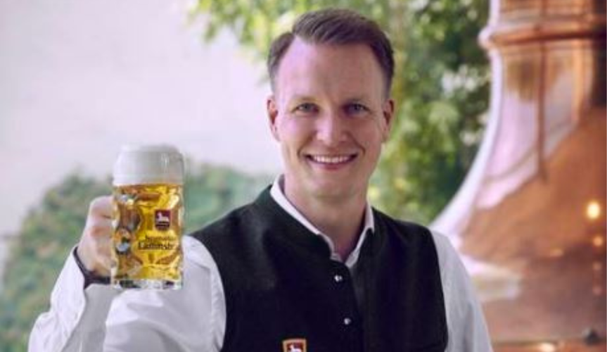 KI generiert: Ein Mann hält ein Bierglas in der Hand, im Hintergrund ist ein Kupferkessel. Text: "Kulmbacher".