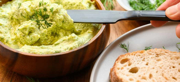 KI generiert: Avocado-Dip in einer Schale mit einem Messer und einer Scheibe Brot.