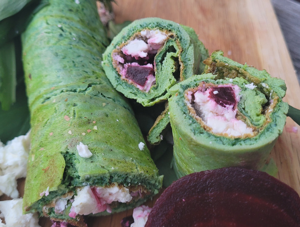 KI generiert: Grüner Wrap gefüllt mit Feta und Rote Bete, auf einem Holzbrett serviert.