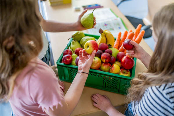 KI generiert: Kinder erkunden eine Kiste voller bunter Früchte und Gemüse.