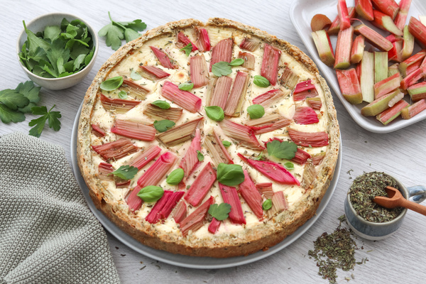 KI generiert: Herzhafte Quiche mit Rhabarber und Kräutern, dekoriert mit frischen Blättern.