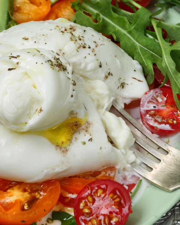 KI generiert: Burrata auf Tomatenscheiben mit Rucola und Gewürzen, serviert mit einer Gabel.