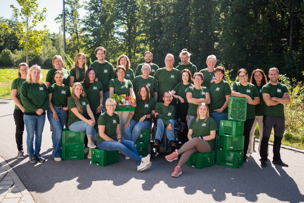 KI generiert: Eine Gruppe von Menschen steht draußen mit grünen Kisten, alle tragen grüne T-Shirts.