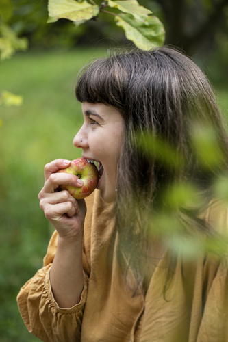 KI generiert: Eine Person isst einen Apfel in einer grünen Umgebung.