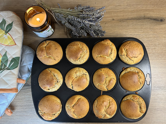 KI generiert: Muffins in einer Backform mit Kerze, Lavendel und Topflappen auf Holztisch.