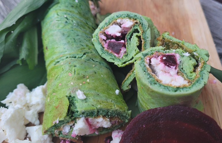 KI generiert: Grüne Wraps gefüllt mit Feta und Rote Bete, angerichtet auf einem Holzbrett mit Bärlauchblättern.
