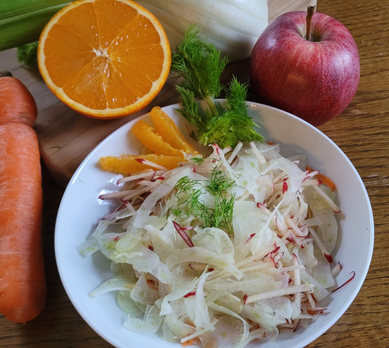KI generiert: Ein frischer Salat mit Fenchel, Apfel und Orange, umgeben von Fenchel, Karotte, Orange und Apfel.