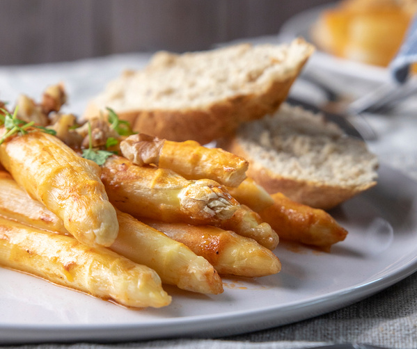 KI generiert: Spargelgericht mit Walnüssen und Brot auf einem Teller.
