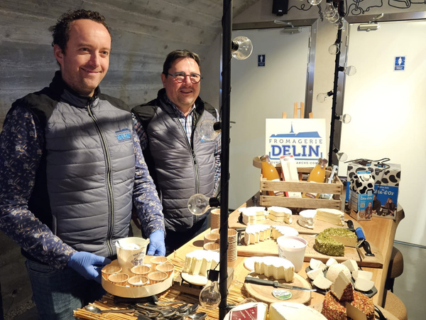 KI generiert: Zwei Männer präsentieren Käse bei einem Stand der "Fromagerie Delin".