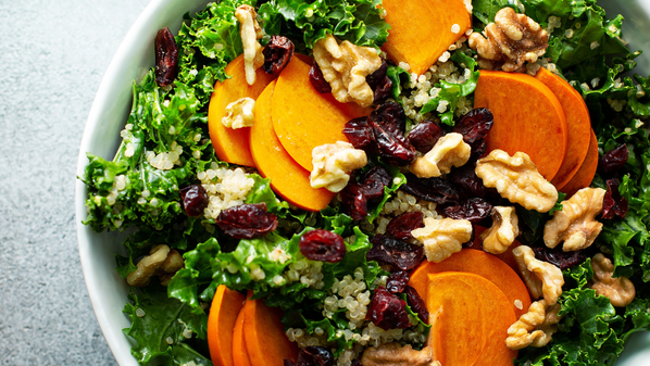 KI generiert: Ein Salat aus Grünkohl, Walnüssen, Quinoa, Kaki und getrockneten Cranberries in einer Schüssel.