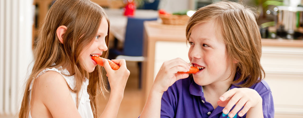KI generiert: Zwei Kinder essen zusammen rote Paprika in einer Küche und lachen.