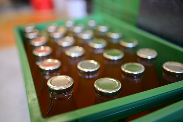 KI generiert: Grüne Kiste mit vielen verschlossenen Glasflaschen, von oben fotografiert.