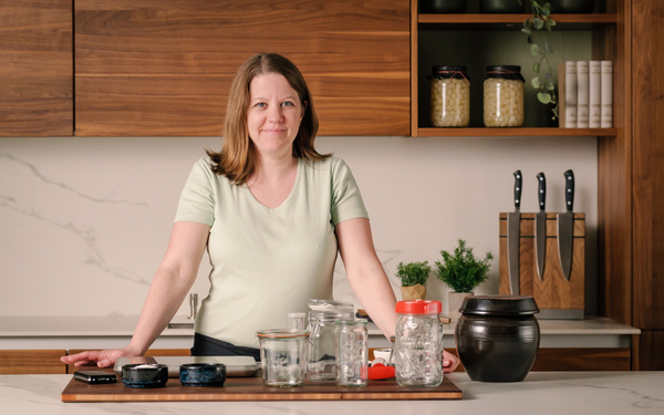 KI generiert: Eine Person in einer Küche mit Gläsern und Behältern auf der Arbeitsfläche.