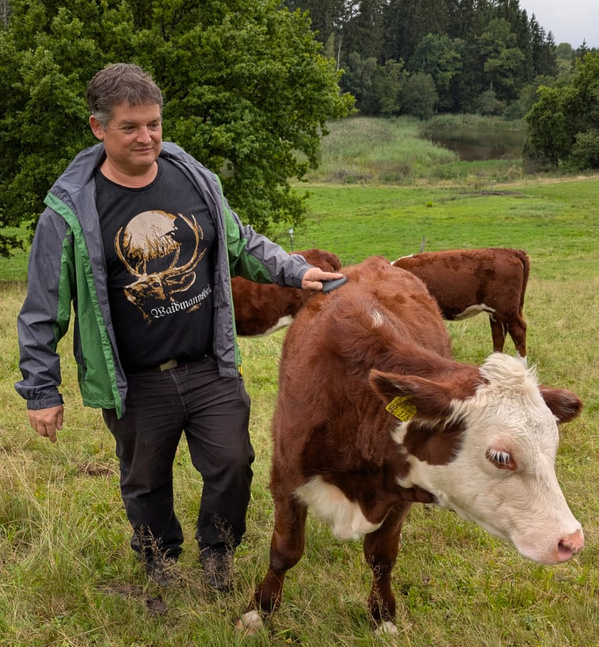 KI generiert: Ein Mann steht auf einer Wiese bei einer Kuh. Text: "Waidmannsheil".