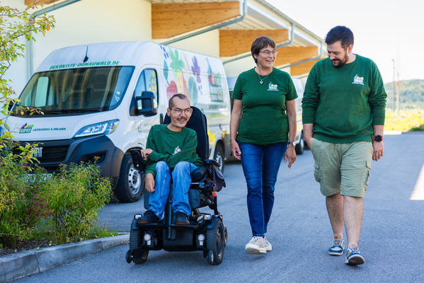 KI generiert: Drei Personen in grünen T-Shirts vor einem Lieferwagen mit "OEKOKISTE-DONAUWALD.DE".