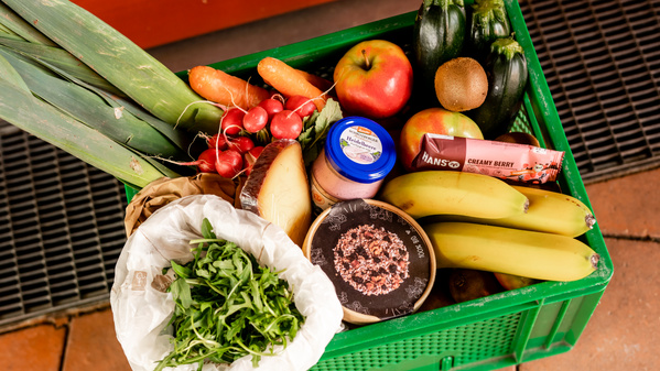 KI generiert: Eine Kiste mit frischem Obst, Gemüse, Brotaufstrich und Snacks.