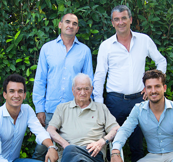 KI generiert: Fünf Männer posieren lächelnd vor einer grünen Hecke.