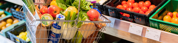 KI generiert: Ein Einkaufskorb mit frischem Obst und Gemüse im Supermarkt.