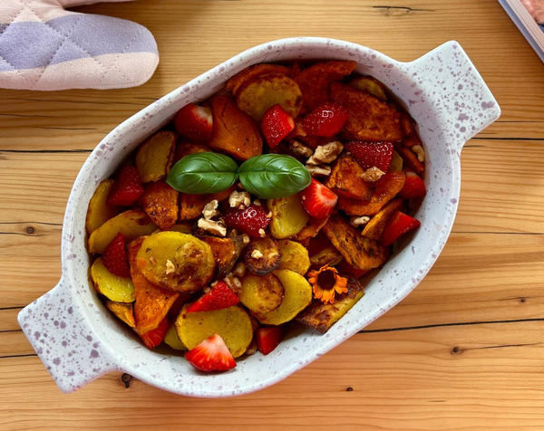 KI generiert: Ofengericht mit Kartoffeln, Süßkartoffeln, Erdbeeren, Walnüssen und Basilikum in einer Schale.