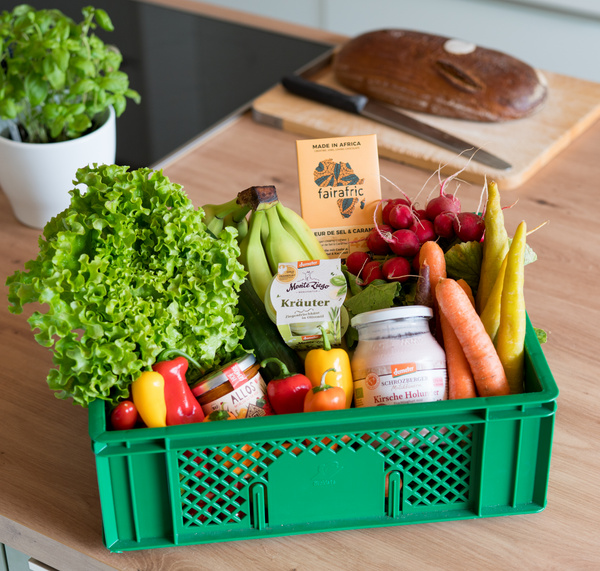 KI generiert: Ein grüner Korb voller Gemüse und Produkte, inklusive Schokolade mit Text "fairafric".