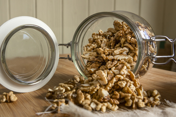 KI generiert: Ein umgekipptes Glas mit Walnüssen auf einem Holztisch.