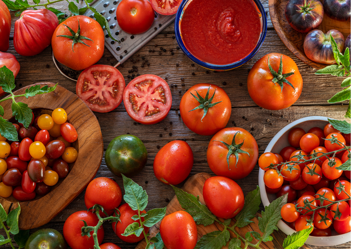 KI generiert: Verschiedene Tomaten auf einem Holztisch, inklusive Tomatensauce und geschnittenen Tomaten.