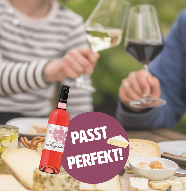 KI generiert: Wein, Käse und Personen beim Anstoßen. Text: "PASST PERFEKT!"