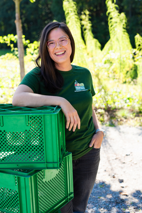 KI generiert: Eine Person lehnt lächelnd an grünen Kisten im Freien.