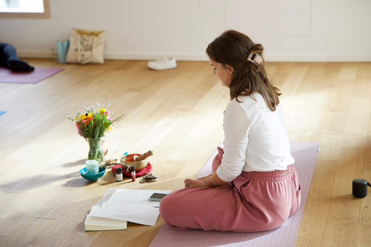 KI generiert: Eine Person meditiert auf einer Yogamatte mit Blumen und Notizen vor sich.