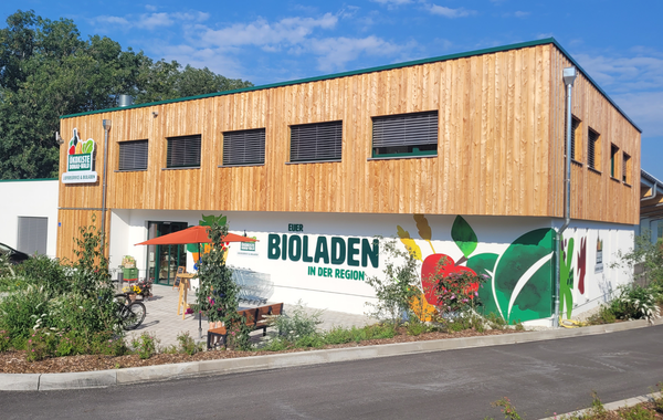 KI generiert: Ein moderner Bioladen mit Holzfassade. Text: "EUER BIOLADEN IN DER REGION".