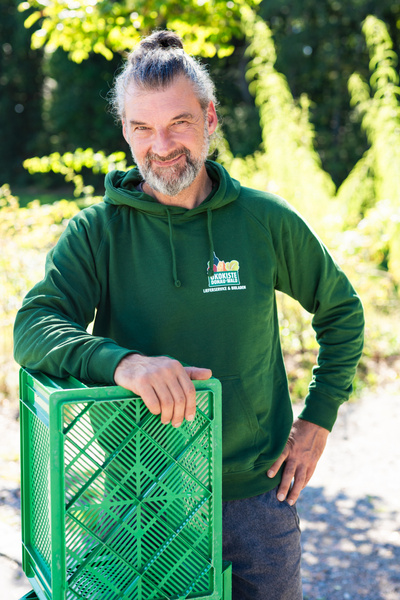 KI generiert: Ein Mann in einem grünen Hoodie lehnt an einer grünen Kiste. Text: "Ökokiste".