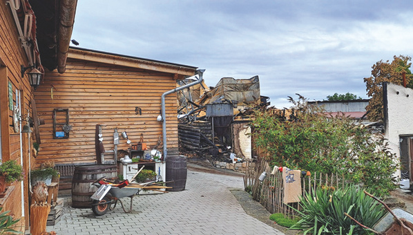KI generiert: Ein Hof mit Gebäuden aus Holz und Stein, Trümmer im Hintergrund.