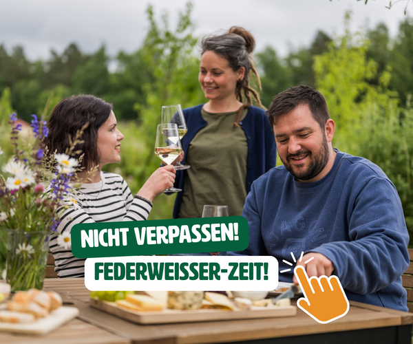 KI generiert: Drei Menschen sitzen draußen am Tisch und trinken Wein.  
Text: "NICHT VERPASSEN! FEDERWEISSER-ZEIT!"